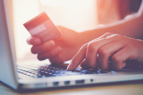Hände, die Kreditkarte und Laptop benutzen. Online-Shopping